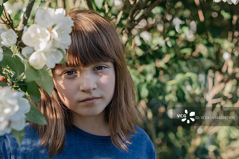 一个女学生的肖像旁边的一个美丽的开花白色灌木。图片素材