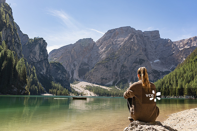 女人坐在湖边欣赏高山山景的背影图片素材