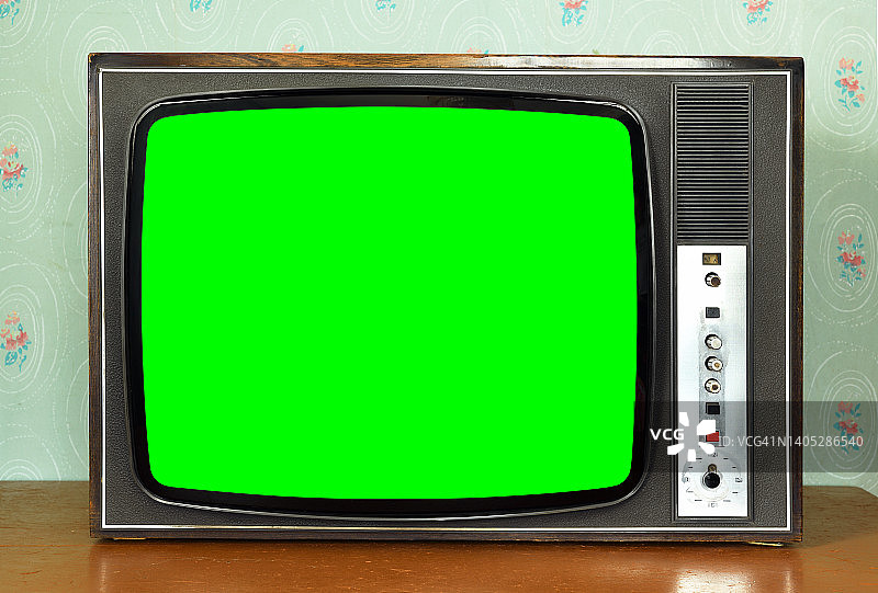 房间里有一台老式的绿色屏幕电视，还有老式的墙纸。20世纪60年代风格的内饰。图片素材