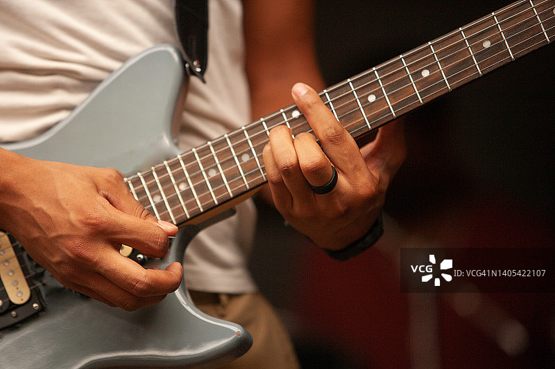 电吉他手灵巧的手和手指在蓝色电吉他上演奏和持有一个音符和曲调图片素材