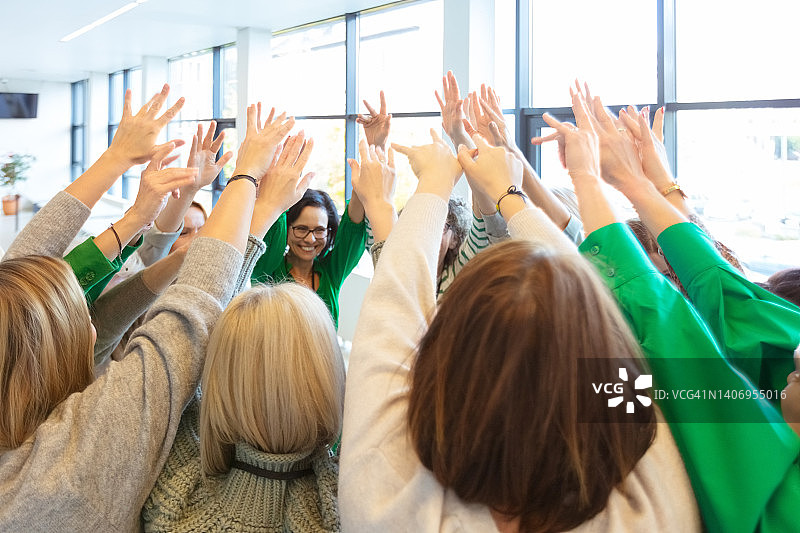 一群妇女在训练时一起举手图片素材