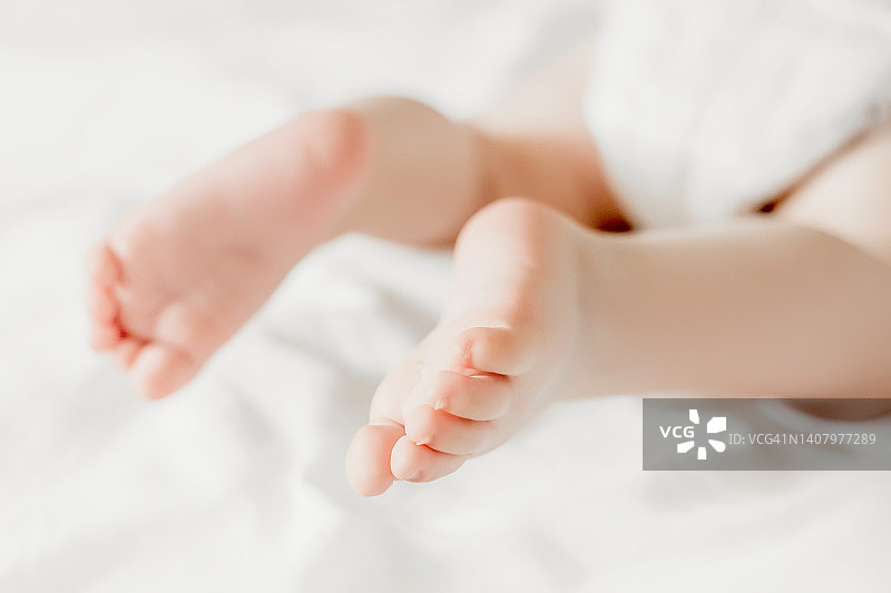 婴儿腿放在白色床单的背景上。副本的空间。乌克兰的新生儿。婴儿的小脚趾图片素材