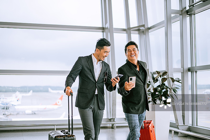 两个商人在现代化的机场候机楼拉着行李箱图片素材