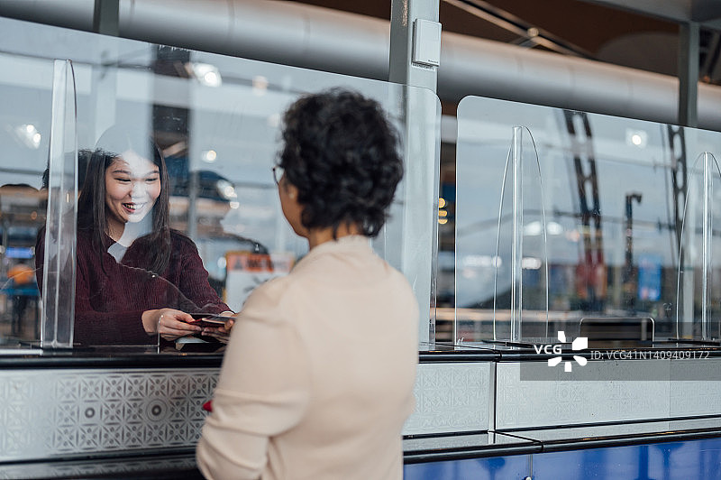 在航空公司值机柜台为旅客发放登机牌的女旅客助理图片素材