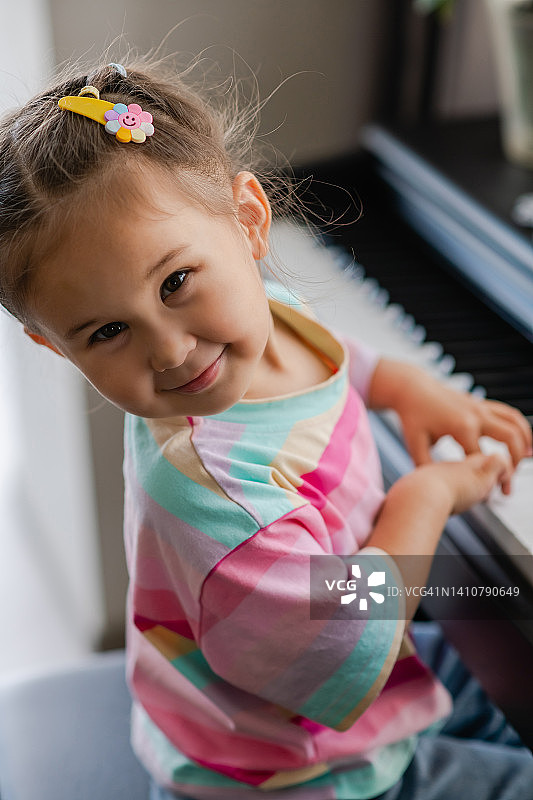 美丽的亚洲小女孩的肖像弹钢琴。图片素材