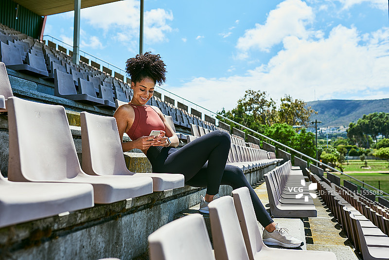 健身运动员在手机上发短信，在完成锻炼、训练或运动后在健身app上更新健康报告目标。活跃的运动女性在网上分享锻炼进展图片素材