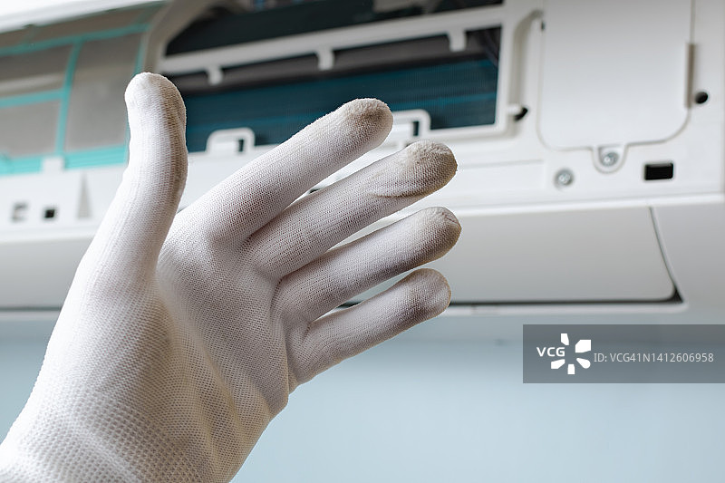维修空调时，一名工人露出一只脏手套。气候系统维护的概念图片素材