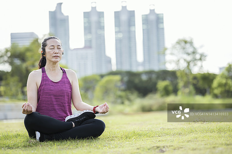 练习瑜伽可以改善心理健康。一名亚洲女性在户外晨练后，通过莲花姿势练习瑜伽以恢复心率。图片素材