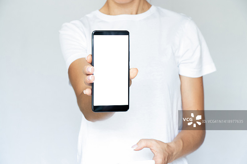 一个穿着白底t恤的女孩手里拿着一个白色屏幕的手机，一个带有手机的模板，一个白色屏幕图片素材