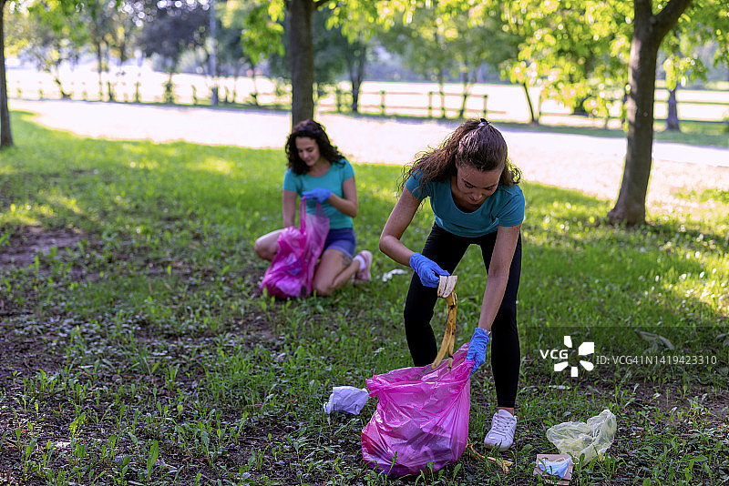 快乐的年轻妇女正在享受从公园收集垃圾的乐趣。图片素材