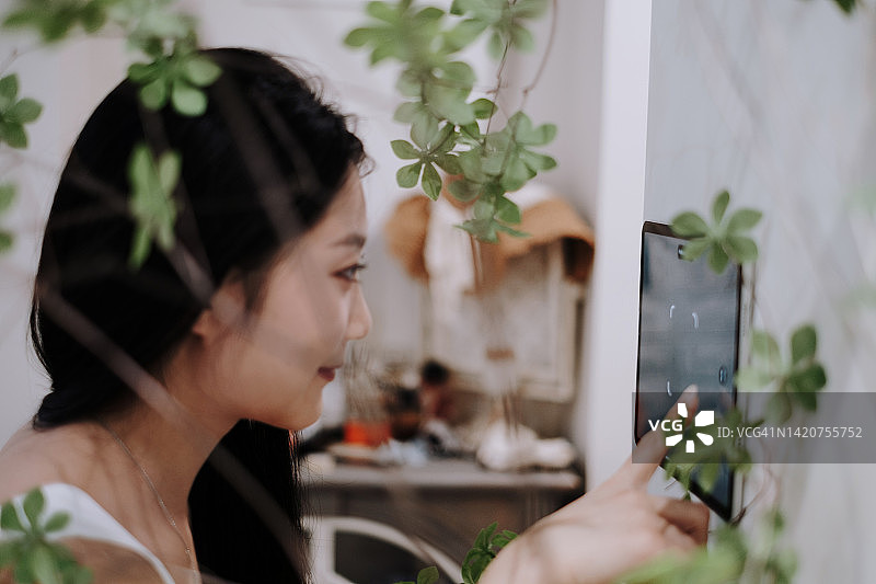 年轻的亚洲女性使用家庭自动化面板图片素材