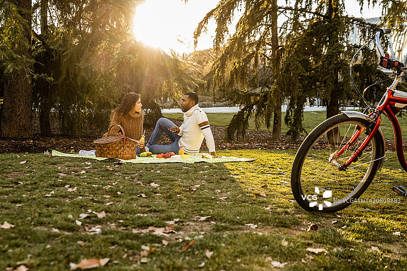 一对年轻的情侣在公园户外野餐。图片素材