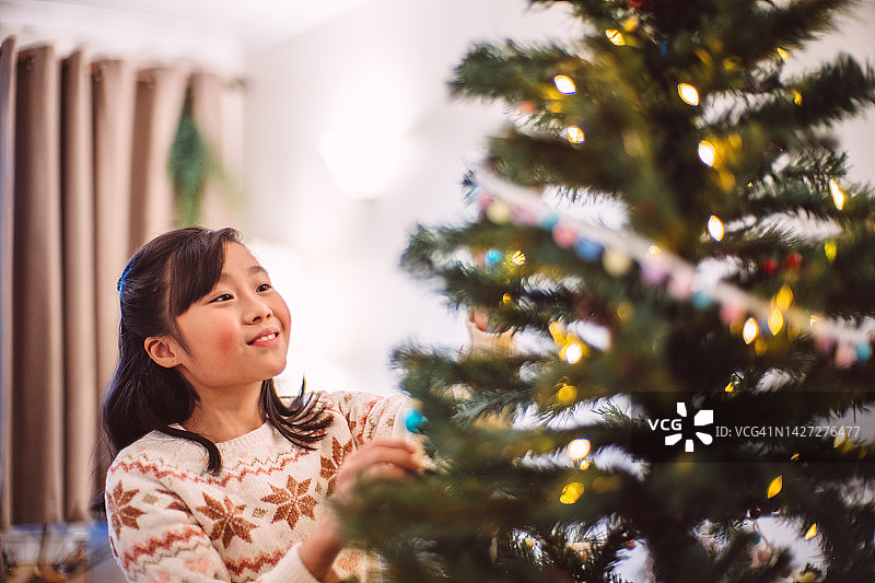 可爱开朗的女孩在家里装饰圣诞树图片素材