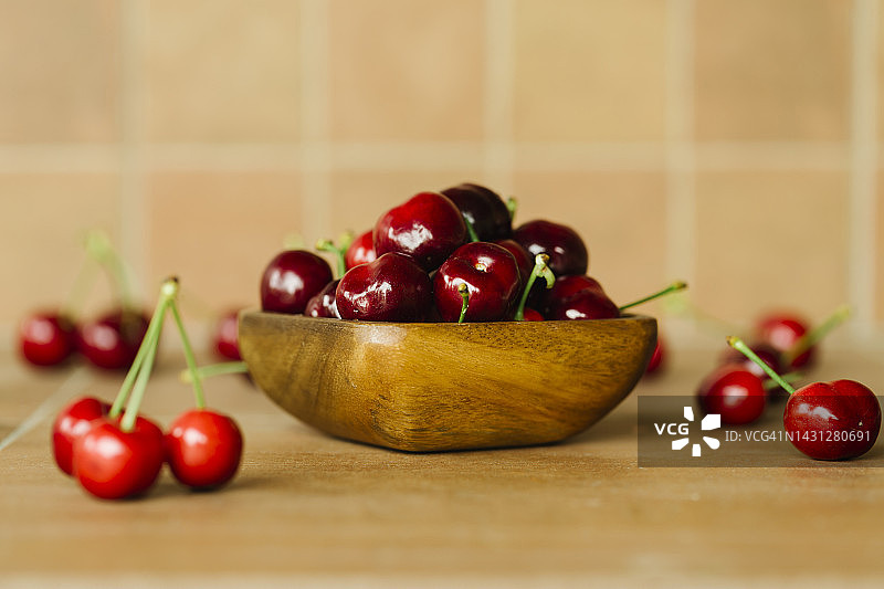 新鲜樱桃在一个木碗在乡村的台面-健康的生活方式和有机生物水果的概念图片素材