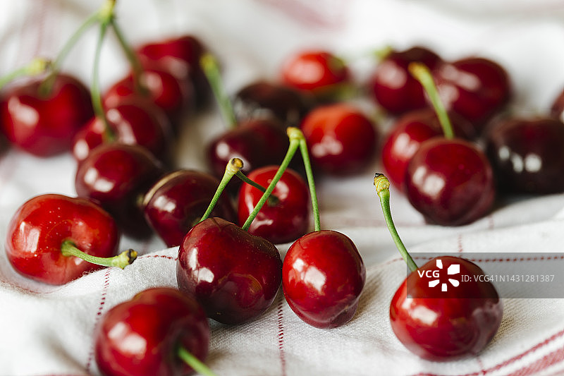 红色条纹餐巾纸上有许多新鲜的樱桃-健康的生活方式和有机生物水果的概念图片素材