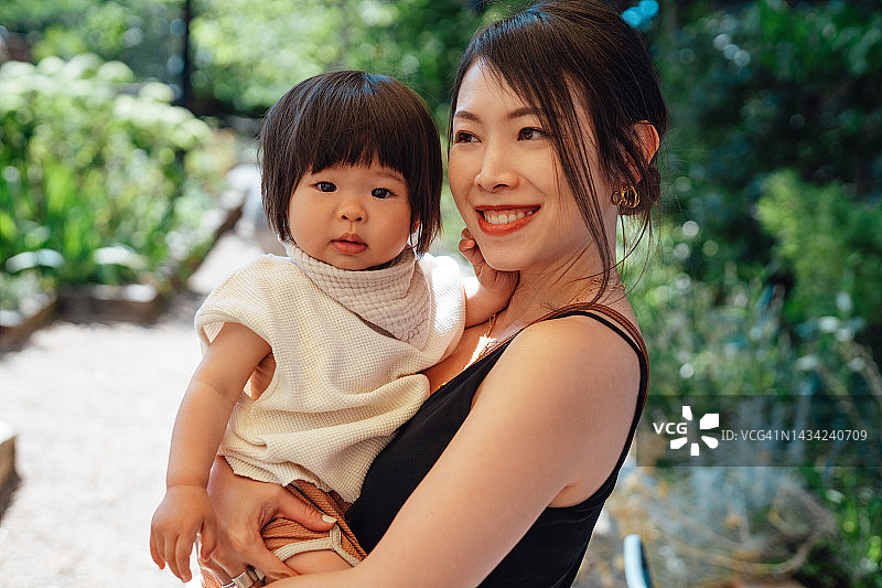 公园里快乐的年轻亚洲母亲和蹒跚学步的女儿的头像图片素材
