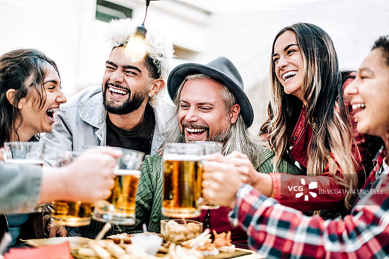 一群快乐的朋友在啤酒花园酒吧喝啤酒-不同年龄的微笑的人在欢乐时光聚会和碰杯啤酒-友谊的生活方式概念图片素材
