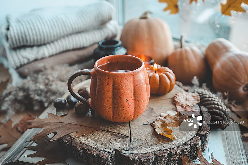 秋天窗台上的静物，窗外的落叶，毛衣，南瓜，一杯茶图片素材