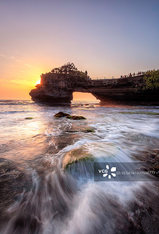 日落时分，塔纳罗特海浪拍打着绿色的岩石图片素材
