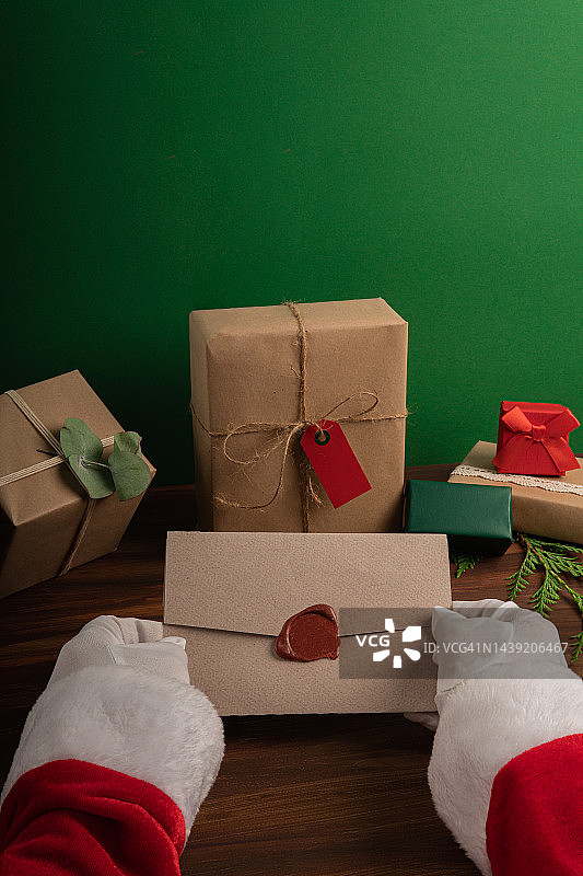 圣诞老人拿着一个优雅的信封在礼物的背景图片素材
