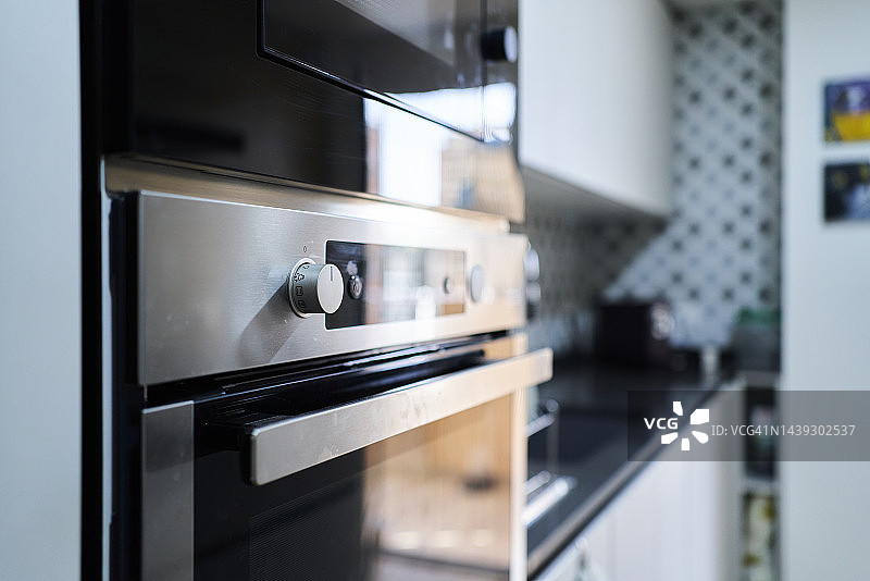 小家庭厨房的侧视图，黑白装饰，选择性聚焦在烤箱上。没有人，在日光下图片素材