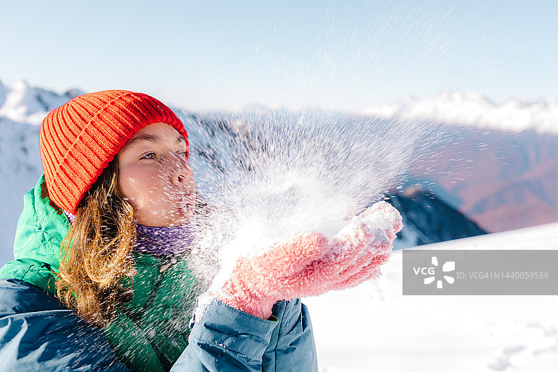 女人玩得很开心，在雪上吹气图片素材