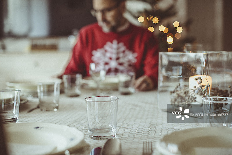 圣诞节，一个男人坐在餐桌前准备晚餐图片素材