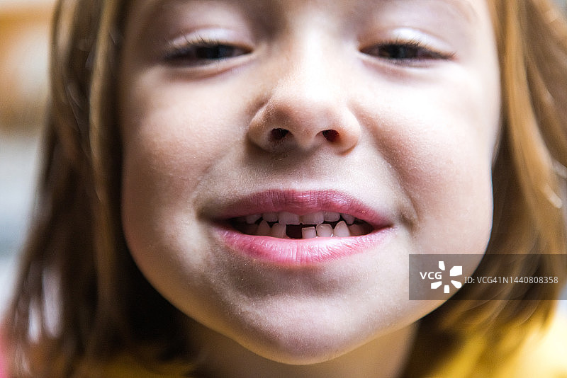 小女孩微笑着张开嘴，露出一颗掉下来的乳牙。生长，牙齿，出牙和童年的概念。图片素材
