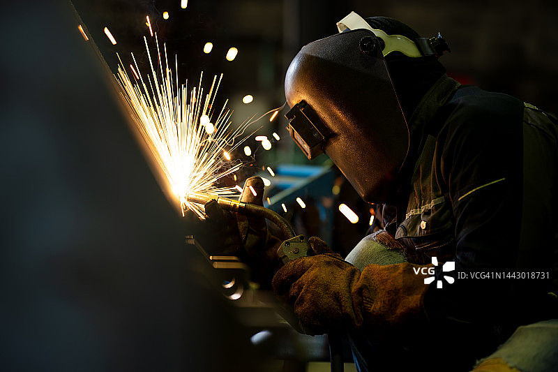 金属加工和焊接技术在建筑业中是必不可少的。在金属结构制造工厂工作的非裔美国男性工业焊工。图片素材