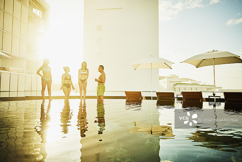 在热带度假胜地，一家人站在泳池边的广角镜头图片素材