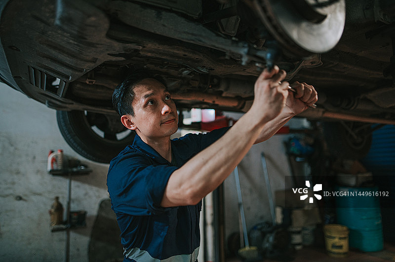 亚裔华人机械师在汽车修理厂检查汽车起落架图片素材