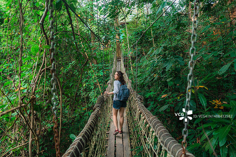 女人走在绳索桥在郁郁葱葱的丛林图片素材