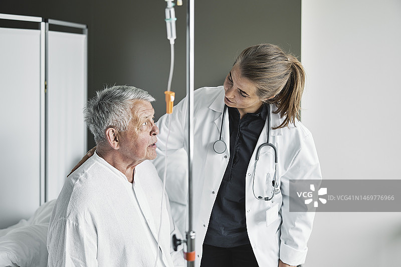 医生坐在病床上与年长的男性病人交谈图片素材