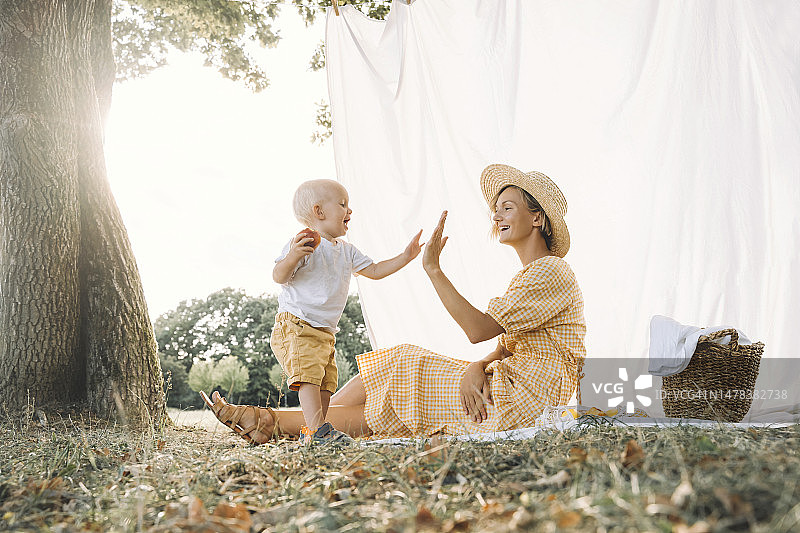 快乐的母亲在公园与儿子击掌图片素材