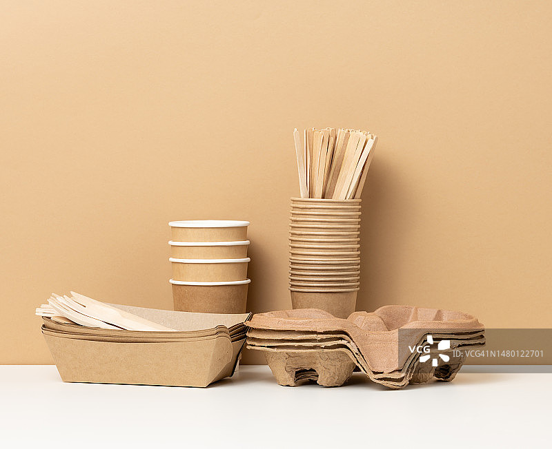 一堆棕色一次性纸杯和白色桌子上的托盘，木制刀叉，罗马尼亚布朗bac图片素材