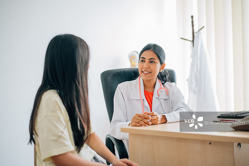 一位亚裔印度女医生正在和一位年轻的中国女病人交谈图片素材