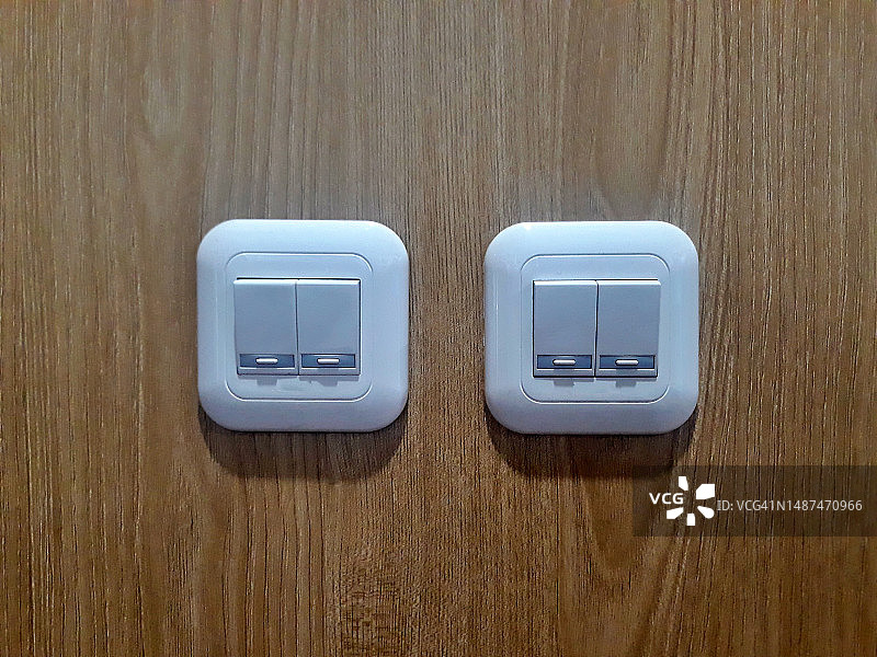 房子或办公室木墙上的白光灯开关按钮。照明装置图片素材
