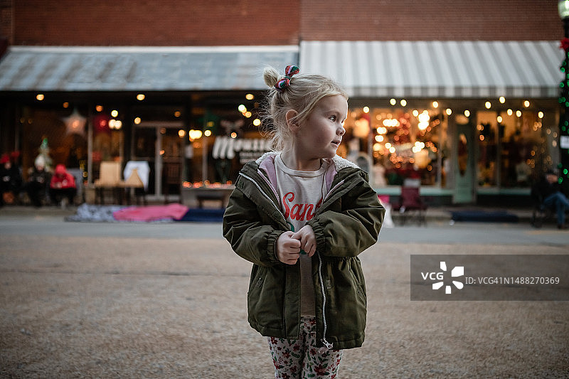 小女孩站在市中心的圣诞商店前图片素材
