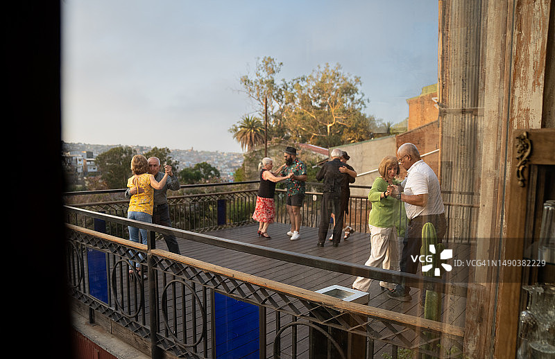 一群老年人都在阳台上与伙伴跳舞，俯瞰着迷人的城市景观图片素材