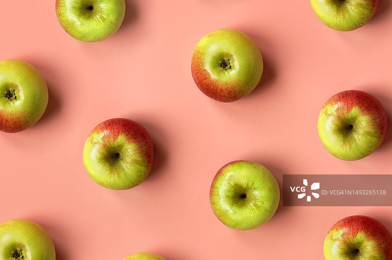 柔和的粉红色背景上有许多苹果。象征丰收、秋天、感恩的自然图案。设计项目的平面铺设图片素材