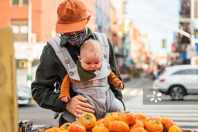 冠状病毒爆发期间，父亲带着女婴在城市街头买柿子图片素材