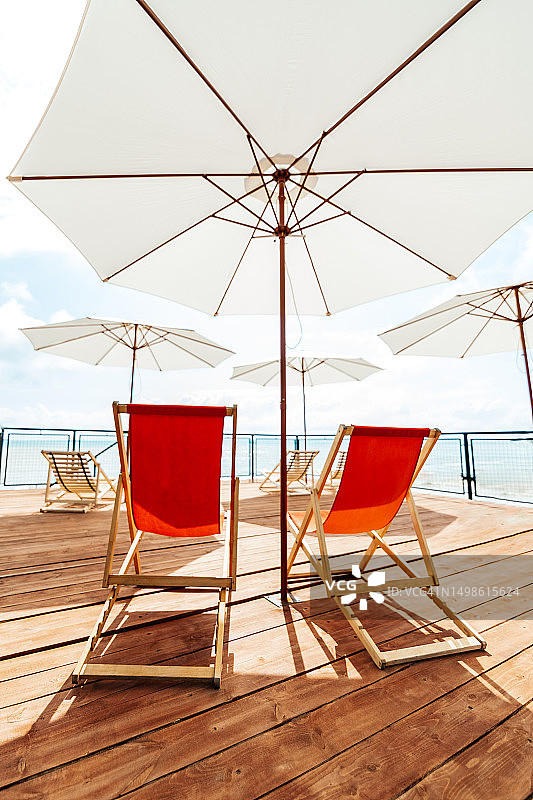 完美的放松点在一个明亮和阳光明媚的日子露台与太阳躺椅和遮阳伞图片素材