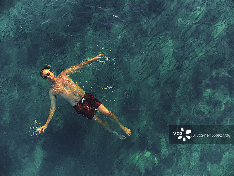 一名男子仰面漂浮在水面上放松空中飞行图片素材