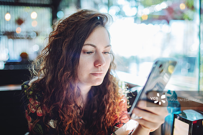 年轻的成年美女在咖啡厅用手机图片素材
