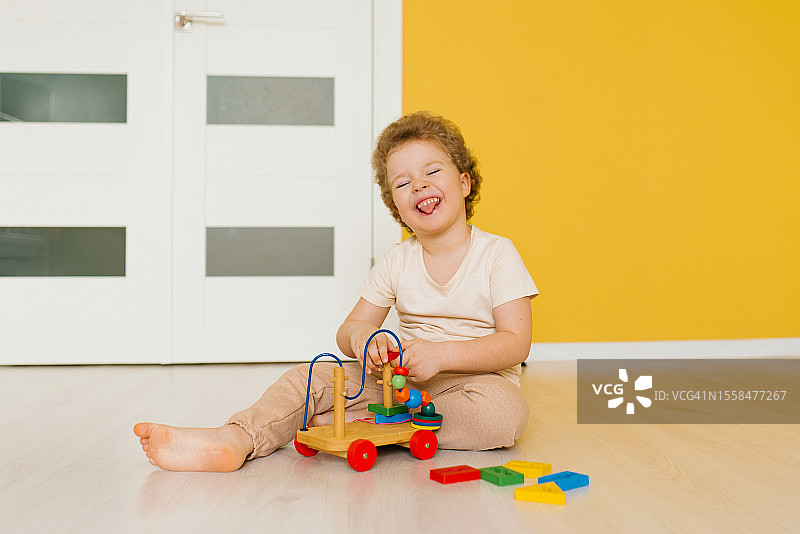 白俄罗斯明斯克，一个开朗快乐的男孩在家里的地板上玩积木玩具图片素材