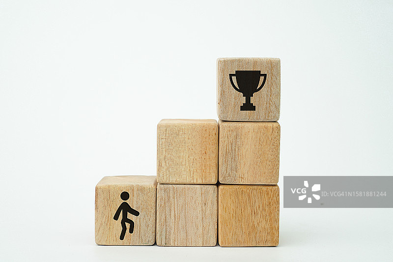 实现目标、成就、抱负和成功的过程的概念，像梯子一样排列的木制立方体，上面有一个人爬梯子的图标，顶部有一个奖杯图片素材