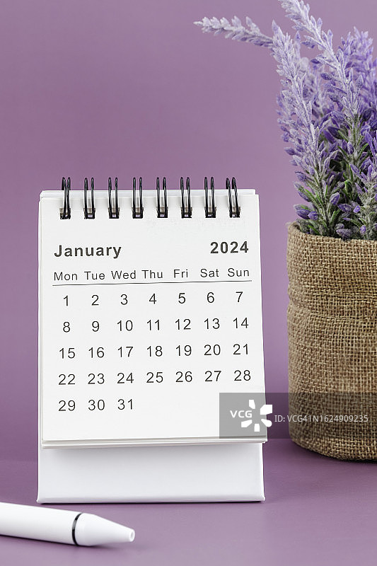日历桌2024:1月是组织者计划和截止日期的月份，手工制作的花和粉红色背景上的白色钢笔。图片素材