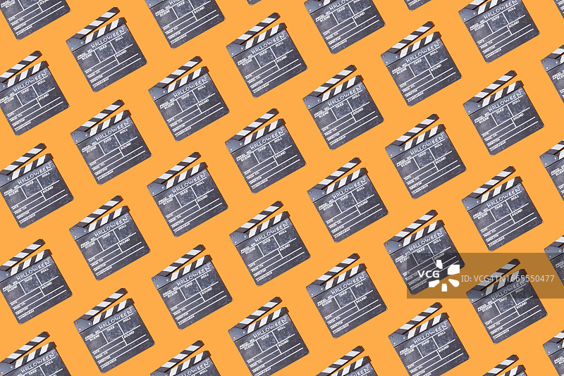 在橙色的背景上，用粉笔写着“万圣节”的木制电影板图案。电影的概念，电影，万圣节，庆祝，电影摄影，恐惧和庆祝。图片素材