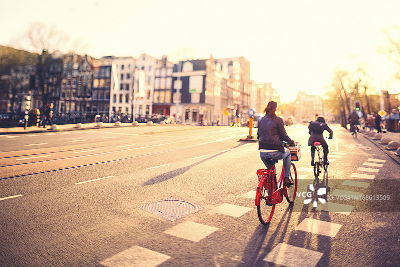 日落时分，人们在阿姆斯特丹的街道上骑自行车图片素材