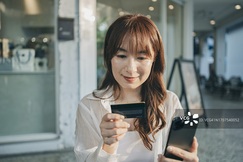 年轻女子用智能手机和信用卡在咖啡馆网上购物图片素材